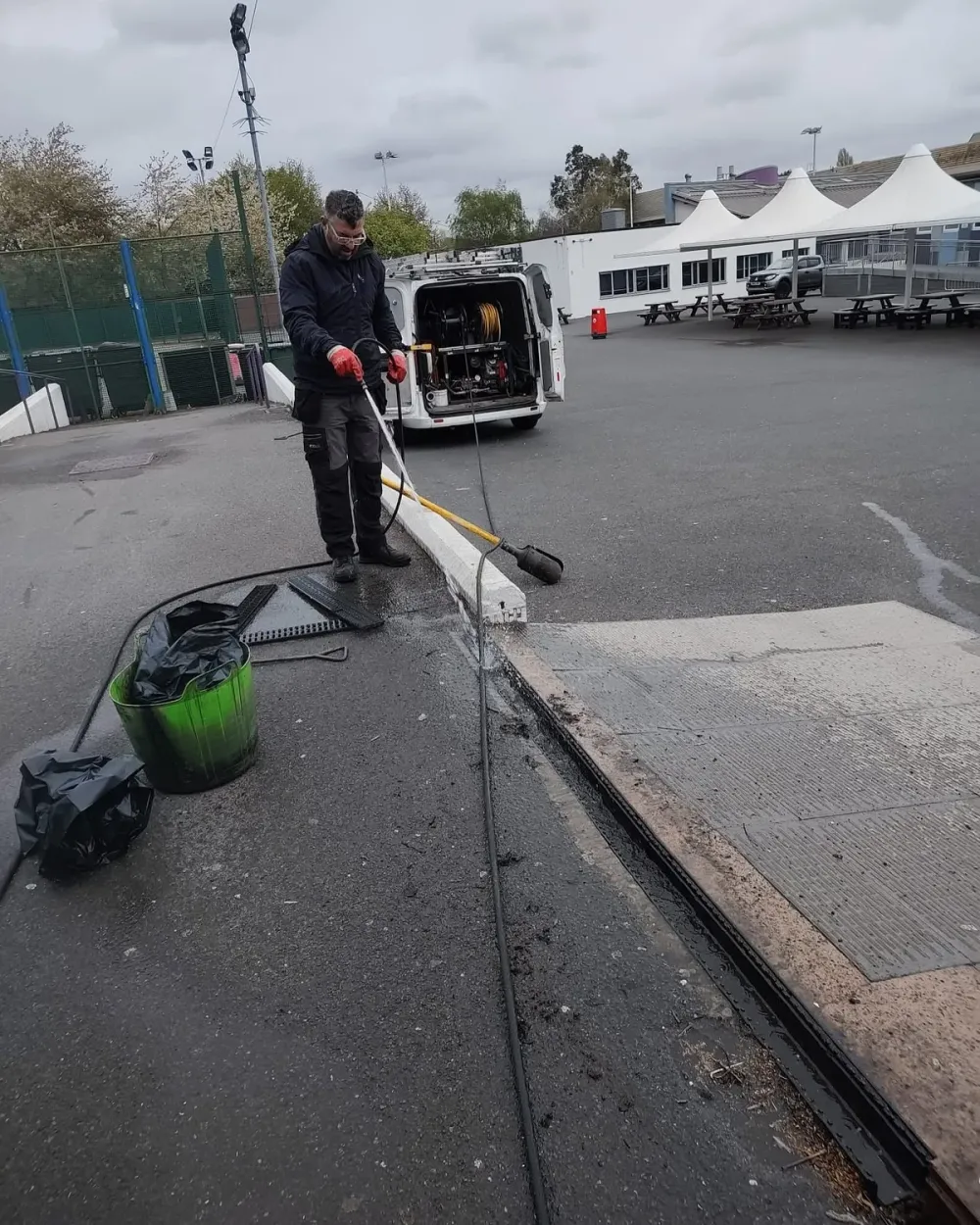 Drainage operative cleaning an outdoor channel using specialist equipment